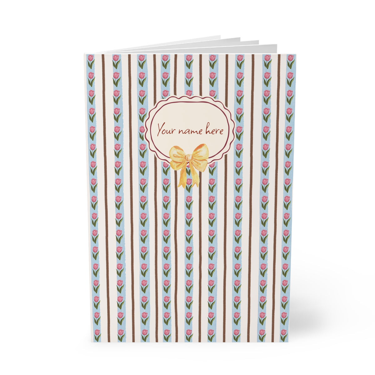 A personalized Softcover A5 Notebook with a vertical striped pattern featuring pink tulips, brown stripes, and a central cream-colored oval label with a gold bow and the text 'Your name here'.