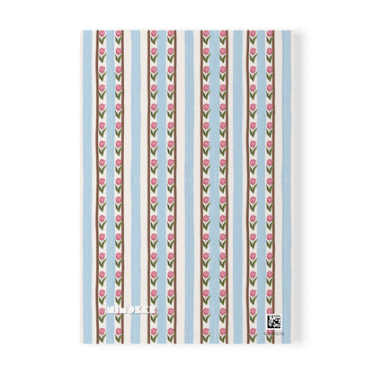 A A5 notebook or journal cover featuring a vertical striped pattern with pink tulips on brown and cream stripes, set against a light blue background. The brand name 'Nimokke' is printed in white near the bottom left.