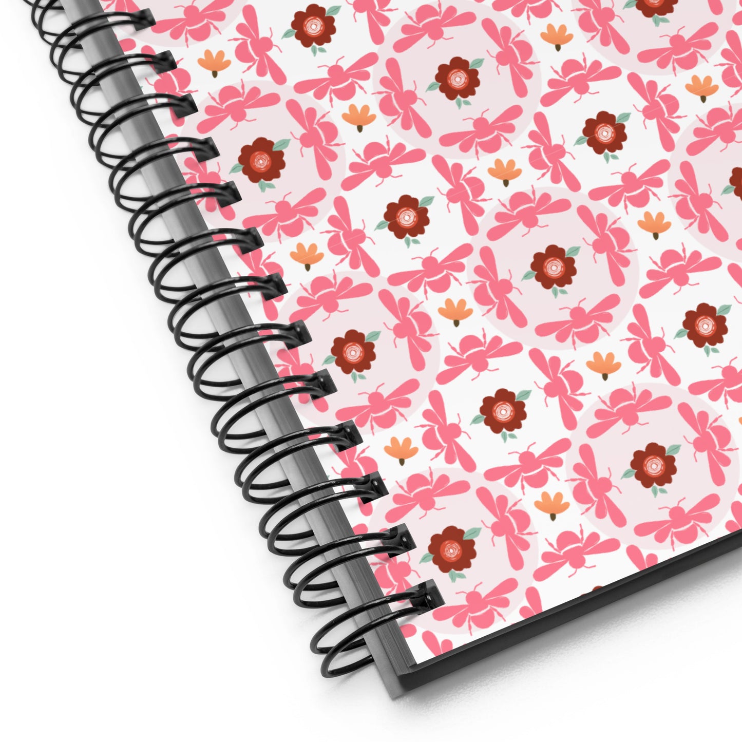 Notebook with pink floral pattern and metal wire-o binding black spiral binding on a white background